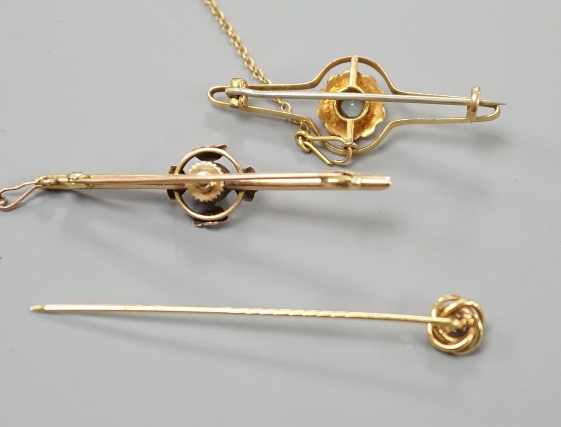 An early 20th century yellow metal and single stone diamond set bar brooch, 46mm, one other gem set bar brooch and a diamond set stick pin, gross weight 6.5 grams.